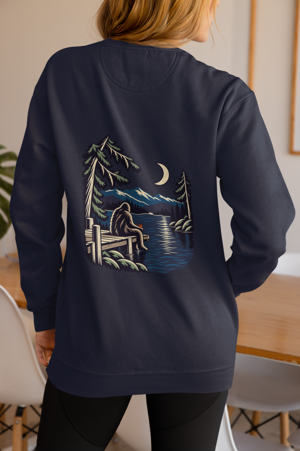 Quiet Hours Garment-Dyed Crewneck in True Navy, worn by a woman seen from behind at home, showing the large print on the back. Digital product mockup.