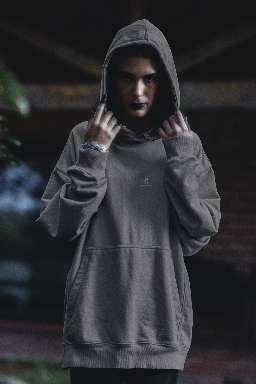 Small Hours Midweight Hoodie in Charcoal, worn by a woman in a dark forest, with the Small Hours logo and portage.camp on the chest. Digital product mockup.