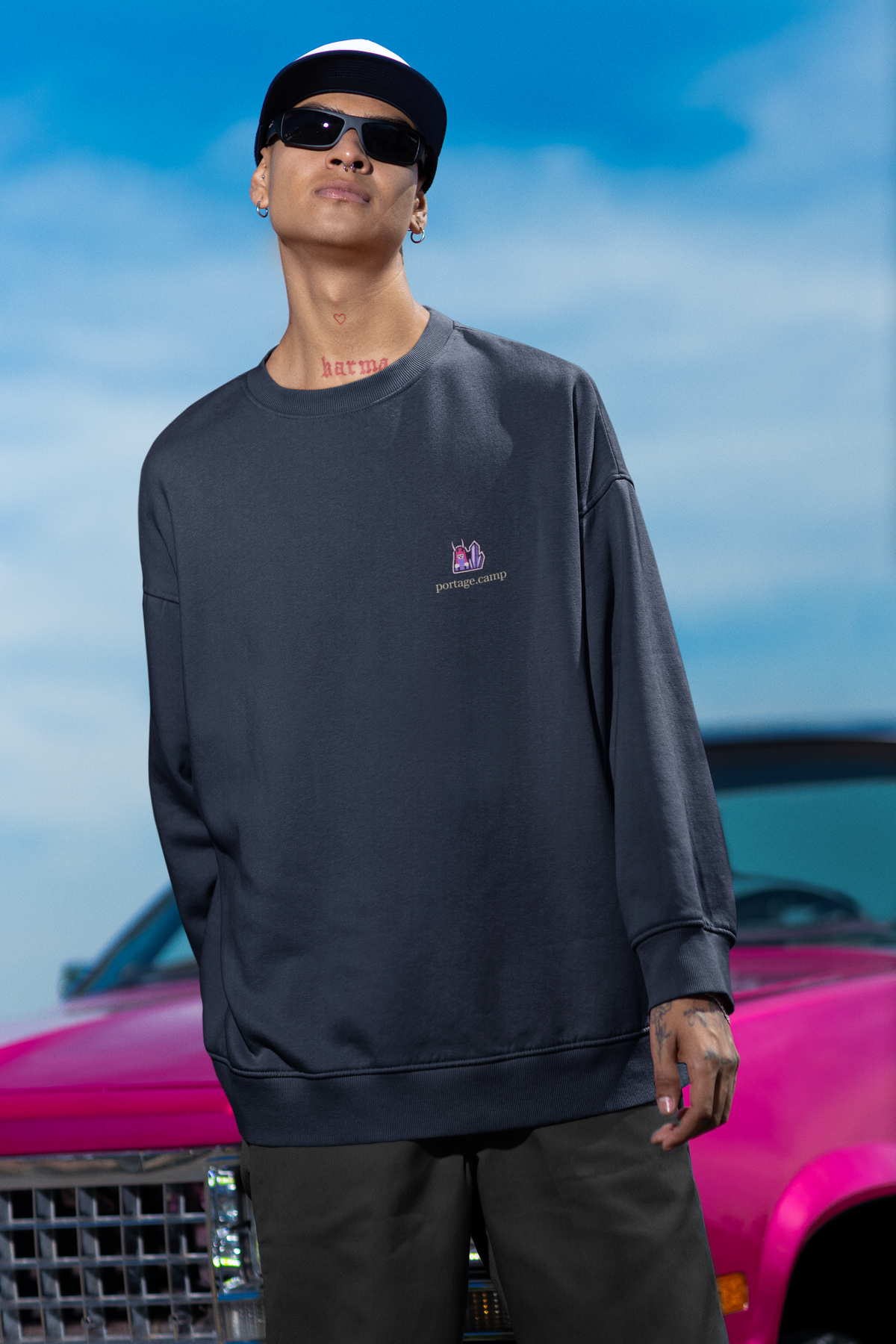 Amethyst After Hours Garment-Dyed Crewneck in True Navy, worn by a man leaning against a car, with the Amethyst After Hours logo and portage.camp on the chest. Digital product mockup.