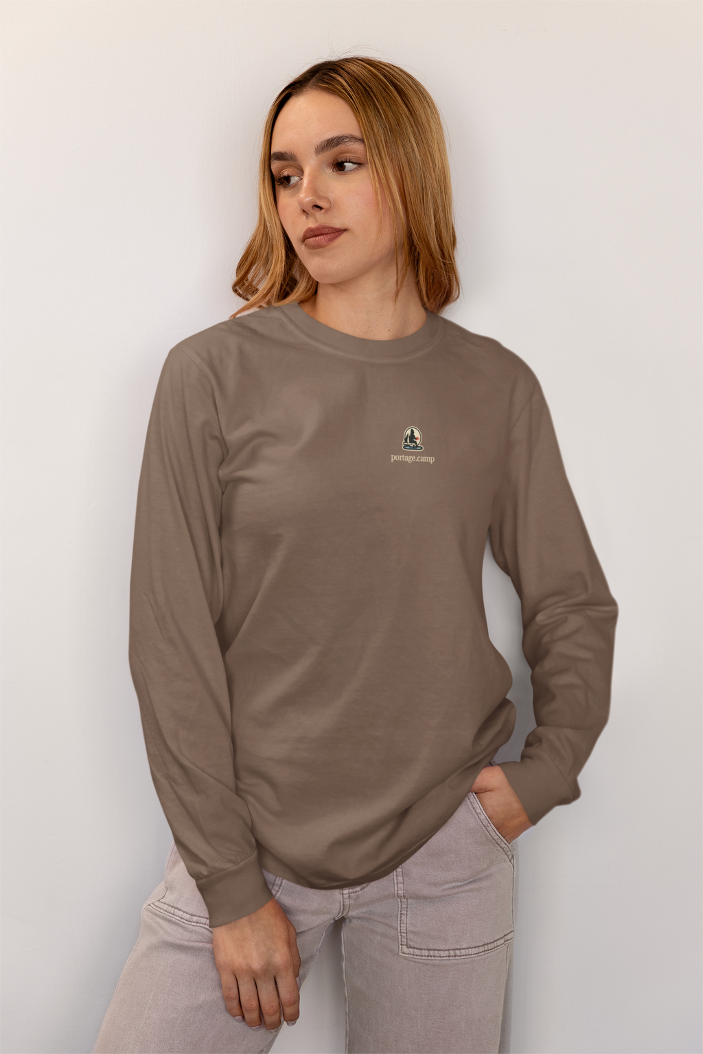 Quiet Hours Garment-Dyed Long-Sleeve Tee in Espresso, worn by a woman at home, with the Quiet Hours logo and portage.camp on the chest. Digital product mockup.
