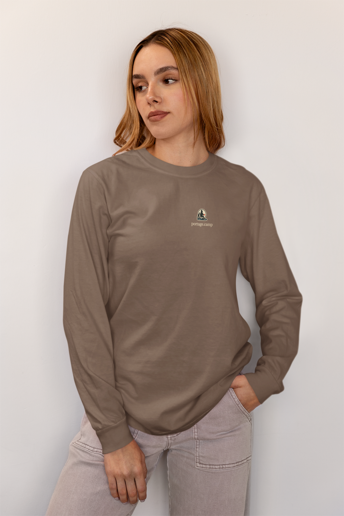 Quiet Hours Garment-Dyed Long-Sleeve Tee in Espresso, worn by a woman at home, with the Quiet Hours logo and portage.camp on the chest. Digital product mockup.
