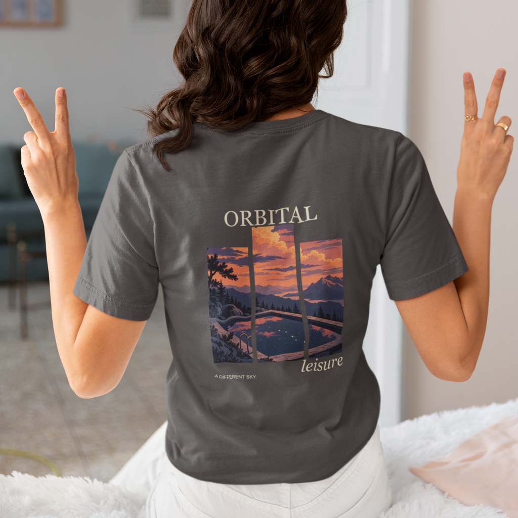 A Different Sky Garment-Dyed Tee in Graphite, worn by a woman seen from behind making peace signs, showing the large print on the back. Digital product mockup.