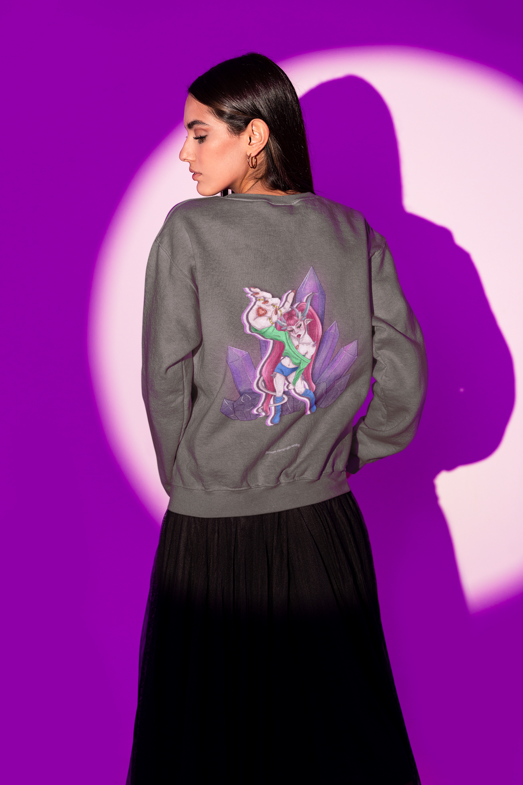 Amethyst After Hours Garment-Dyed Crewneck in Pepper, worn by a woman seen from behind in a studio under purple light, showing the large print on the back. Digital product mockup.