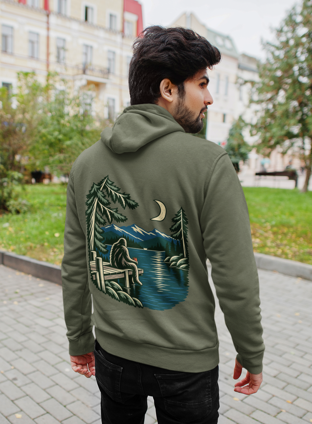 Quiet Hours Zip Hoodie in Military Green, worn by a man seen from behind on a quiet city street, showing the large print on the back. Digital product mockup.