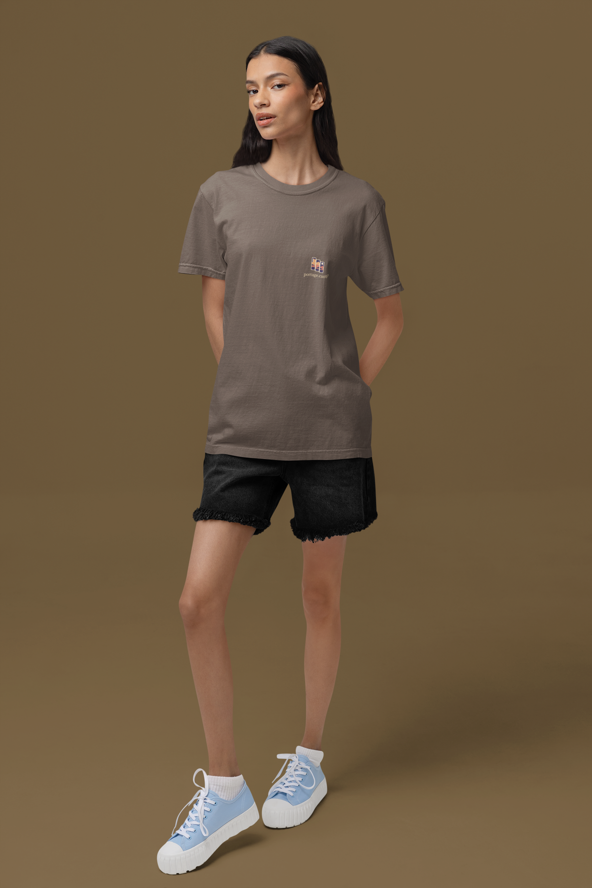 Stay for the Sky Garment-Dyed Tee in Espresso, worn by a woman standing in a studio, with the Stay for the Sky logo and portage.camp on the chest. Digital product mockup.