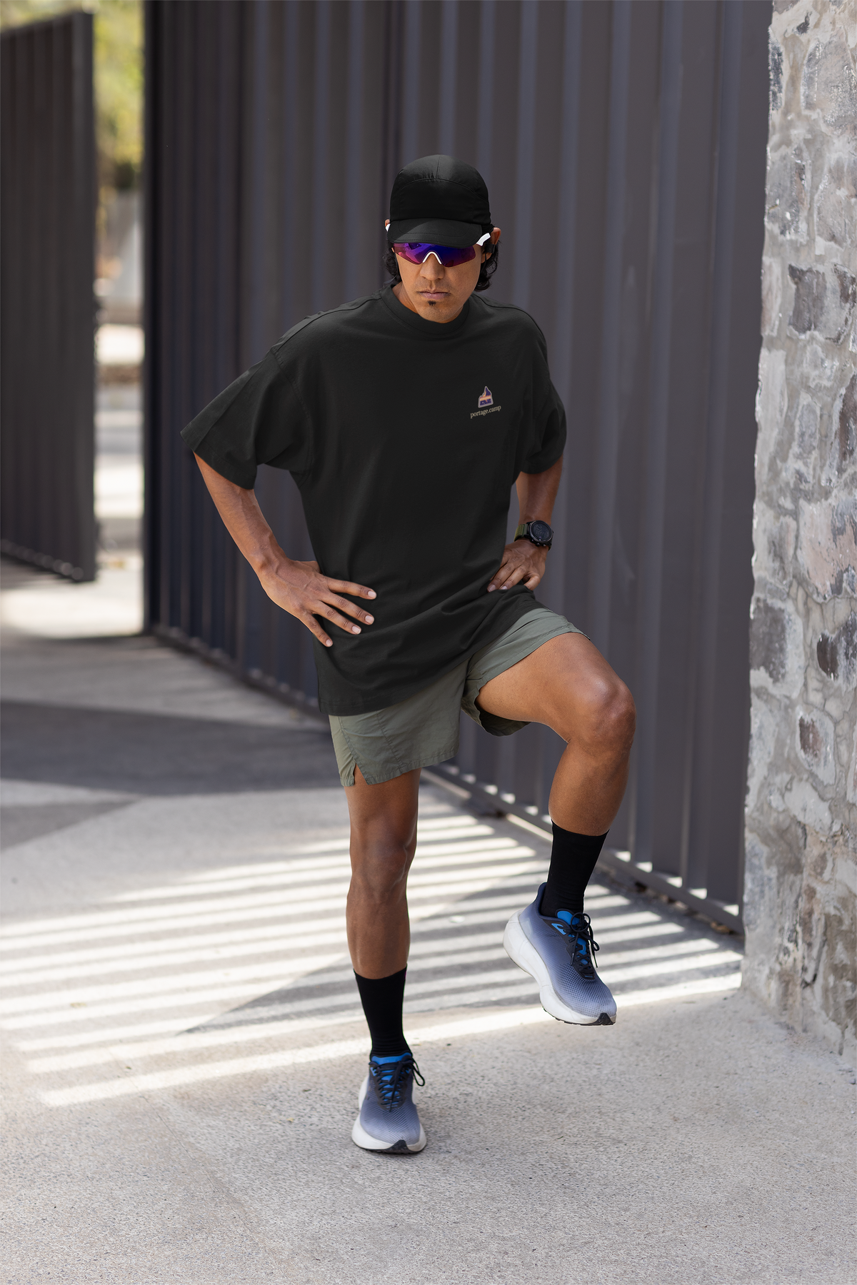 A Different Sky Garment-Dyed Tee in Black, worn by a man stretching before a run, with the A Different Sky logo and portage.camp on the chest. Digital product mockup.