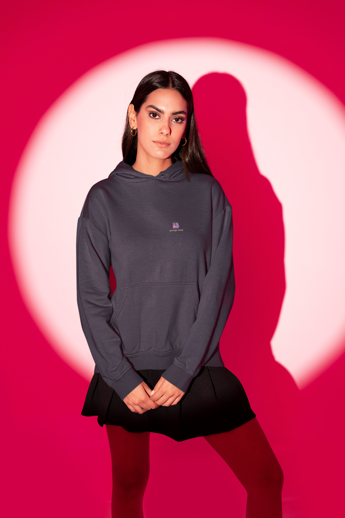 Amethyst After Hours Midweight Hoodie in Classic Navy, worn by a woman in a red-lit studio, with the Amethyst After Hours logo and portage.camp on the chest. Digital product mockup.