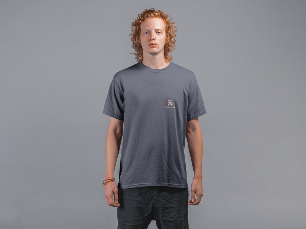 Edge of Evening Garment-Dyed Tee in Navy, worn by a man against a plain grey wall, with the Edge of Evening logo and portage.camp on the chest. Digital product mockup.