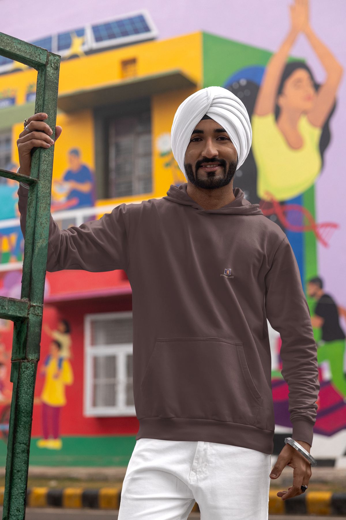 Open Late Heavyweight Hoodie in Brown, worn by a man in a turban on a busy street, with the Open Late logo and portage.camp on the left chest. Digital product mockup.
