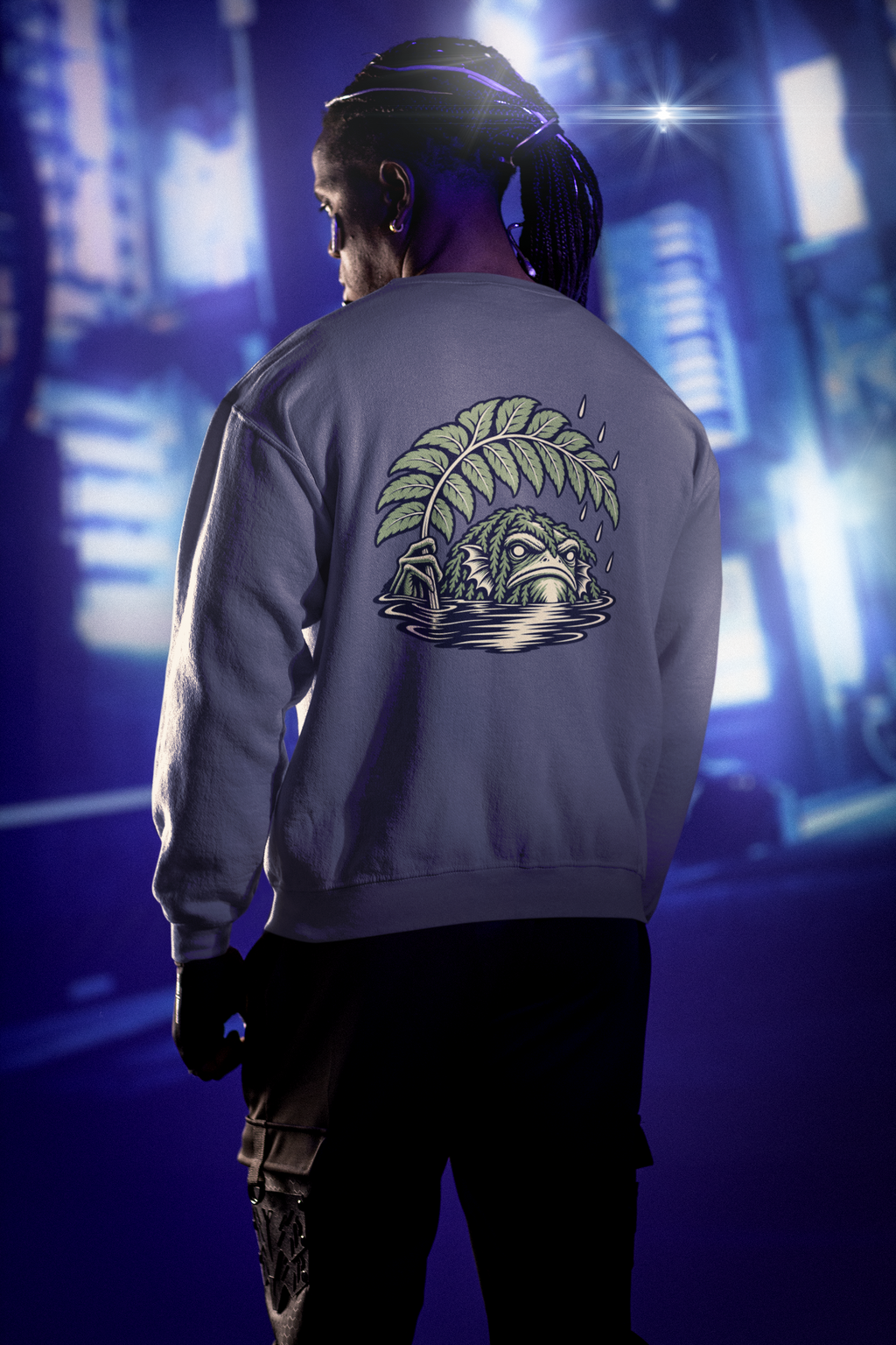 Rain Check Garment-Dyed Crewneck in Denim, worn by a man seen from behind under neon city lights, showing the large print on the back. Digital product mockup.