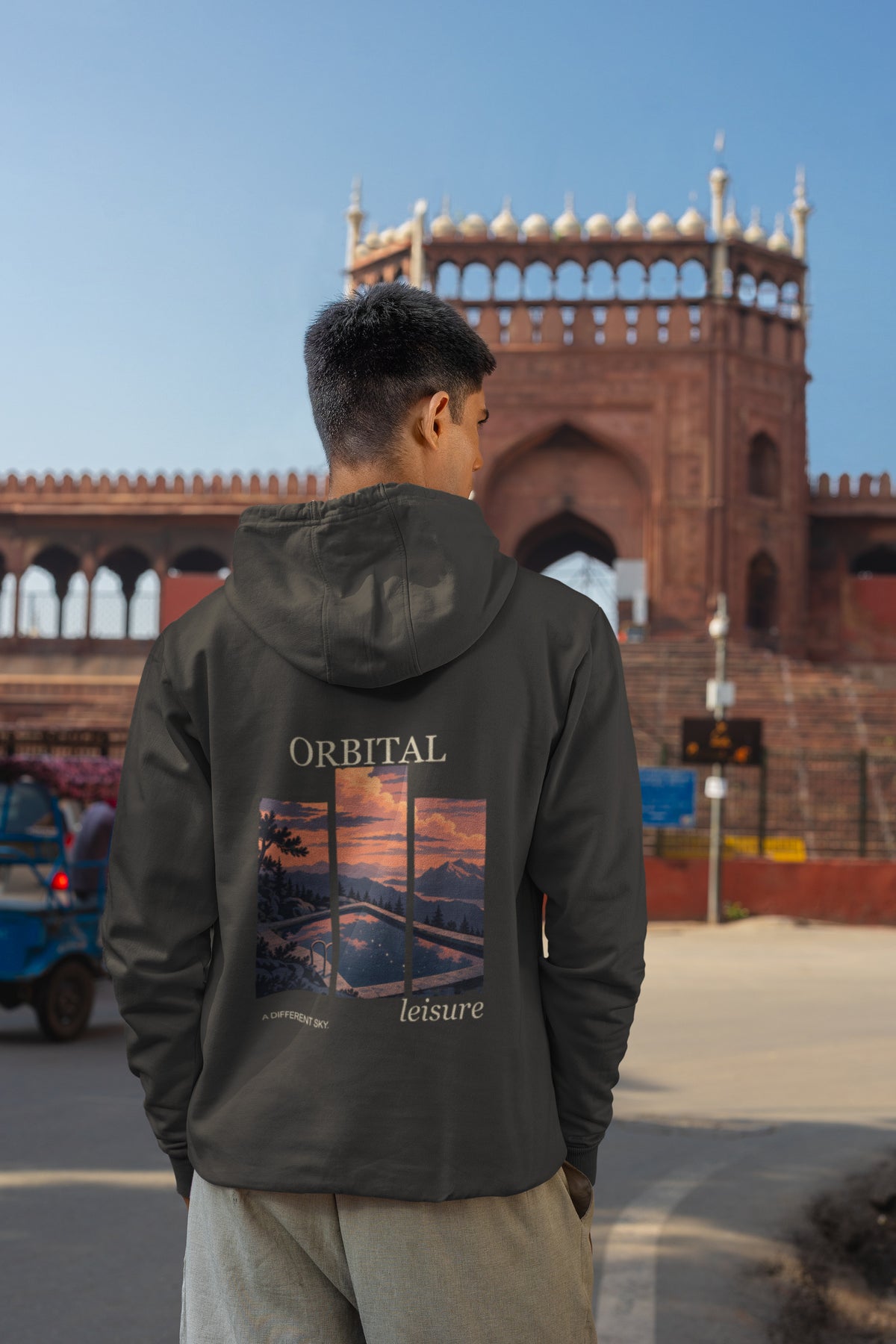 A Different Sky Zip Hoodie in Black, worn by a man seen from behind on a city street, showing the large print on the back. Digital product mockup.