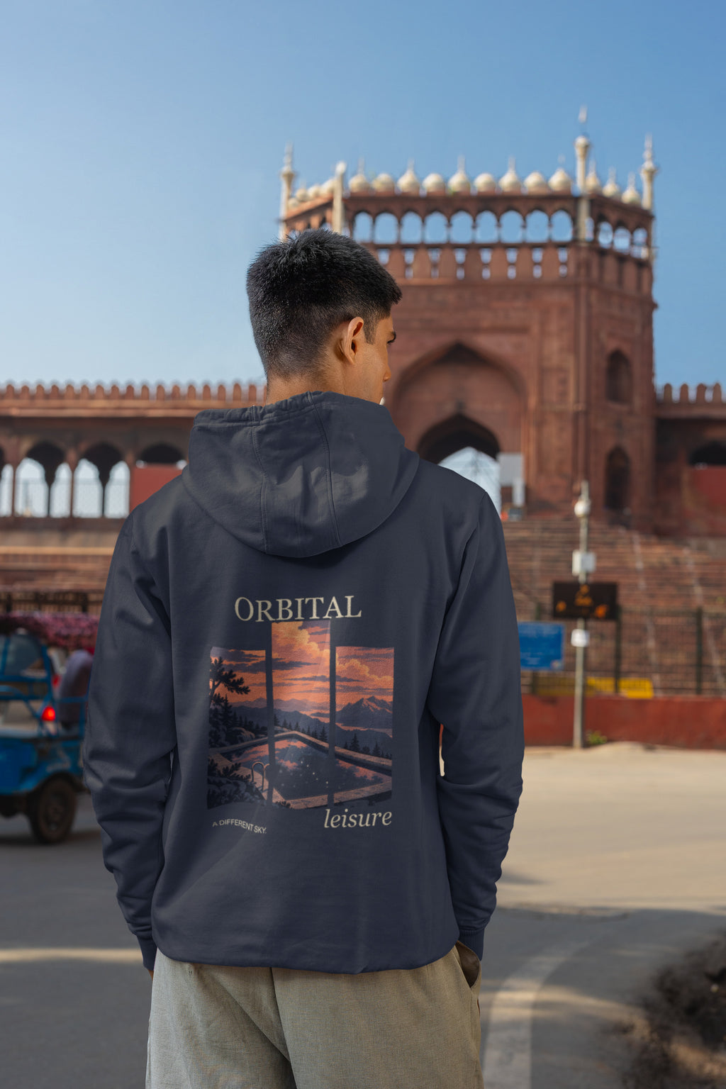 A Different Sky Zip Hoodie in Navy, worn by a man seen from behind on a city street, showing the large print on the back. Digital product mockup.
