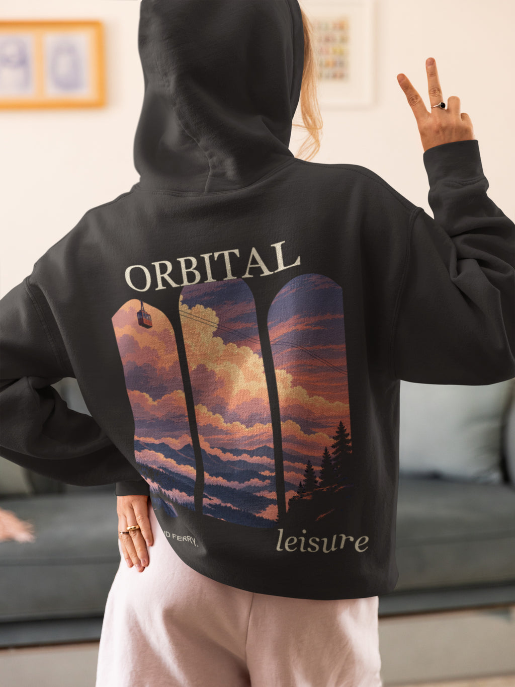 Cloud Ferry Zip Hoodie in Black, worn by a woman seen from behind at home, making a peace sign, showing the large print on the back. Digital product mockup.