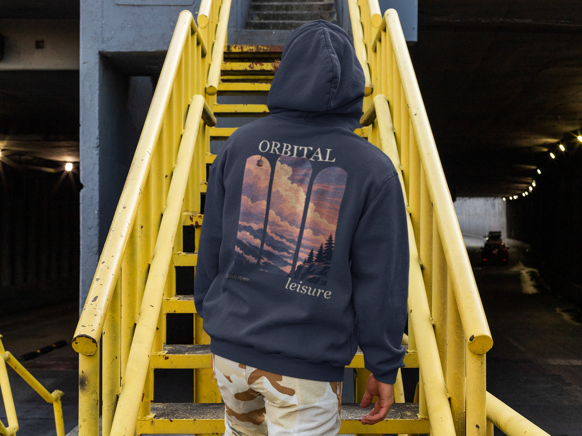 Cloud Ferry Zip Hoodie in Navy, worn by a man seen from behind climbing a yellow metal staircase, showing the large print on the back. Digital product mockup.
