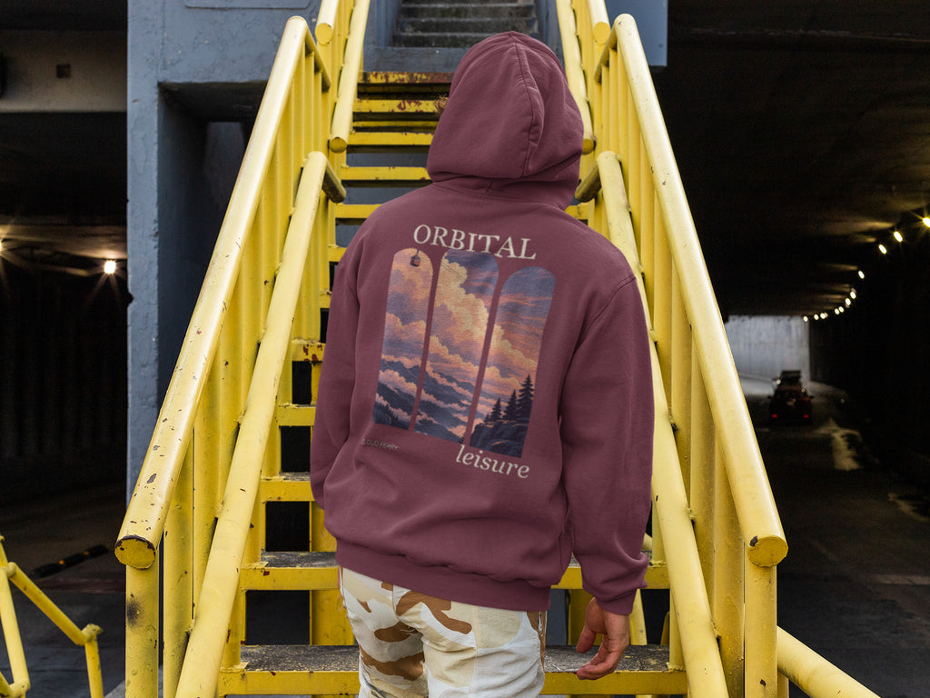Cloud Ferry Zip Hoodie in Maroon, worn by a man seen from behind climbing a yellow metal staircase, showing the large print on the back. Digital product mockup.