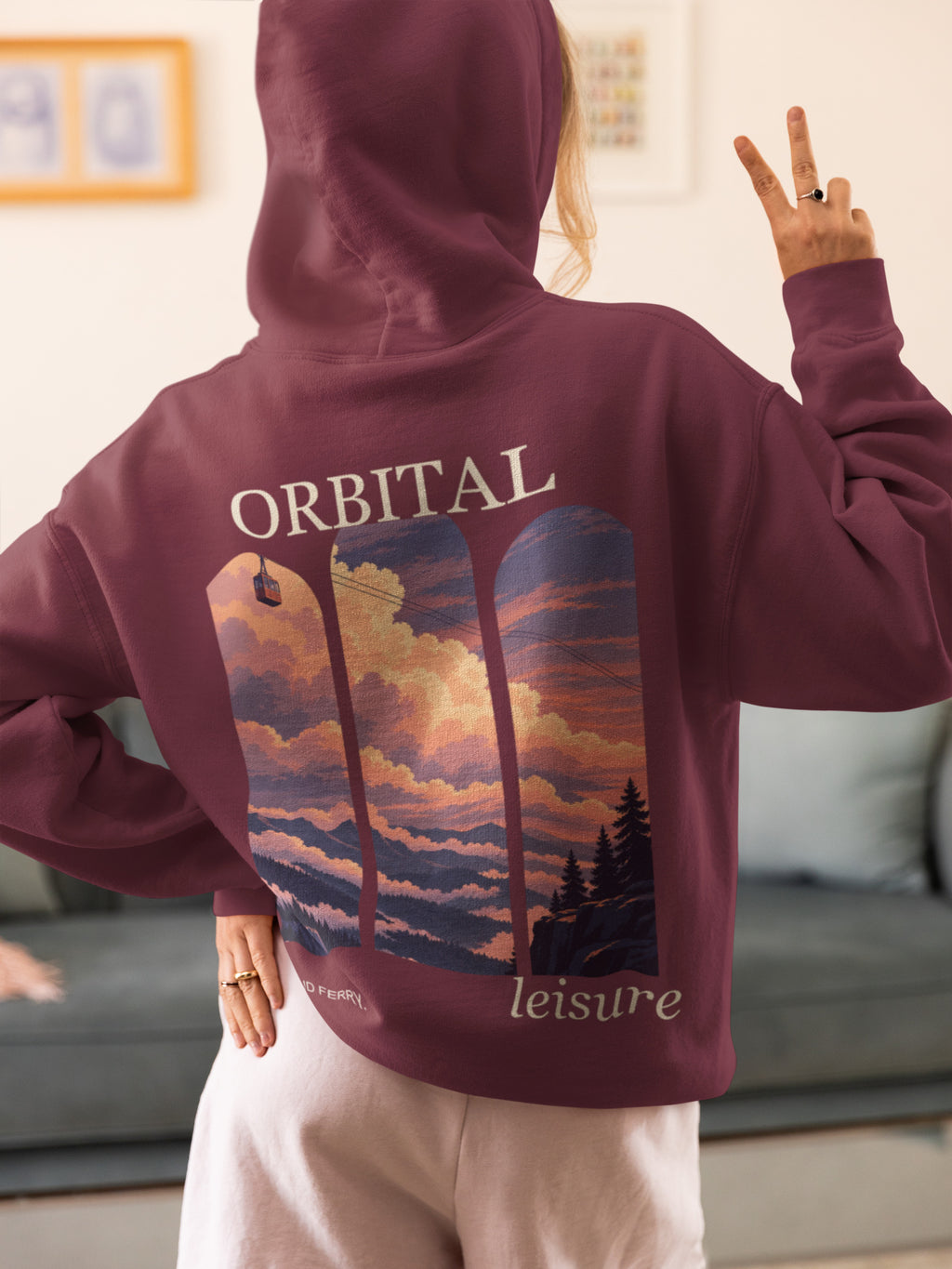Cloud Ferry Zip Hoodie in Maroon, worn by a woman seen from behind at home, making a peace sign, showing the large print on the back. Digital product mockup.