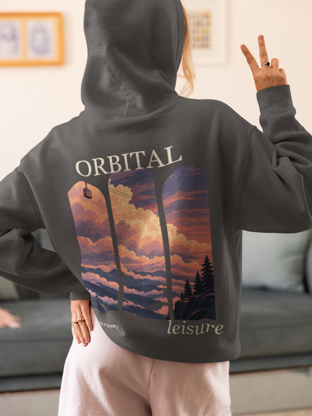 Cloud Ferry Zip Hoodie in Dark Heather, worn by a woman seen from behind at home, making a peace sign, showing the large print on the back. Digital product mockup.