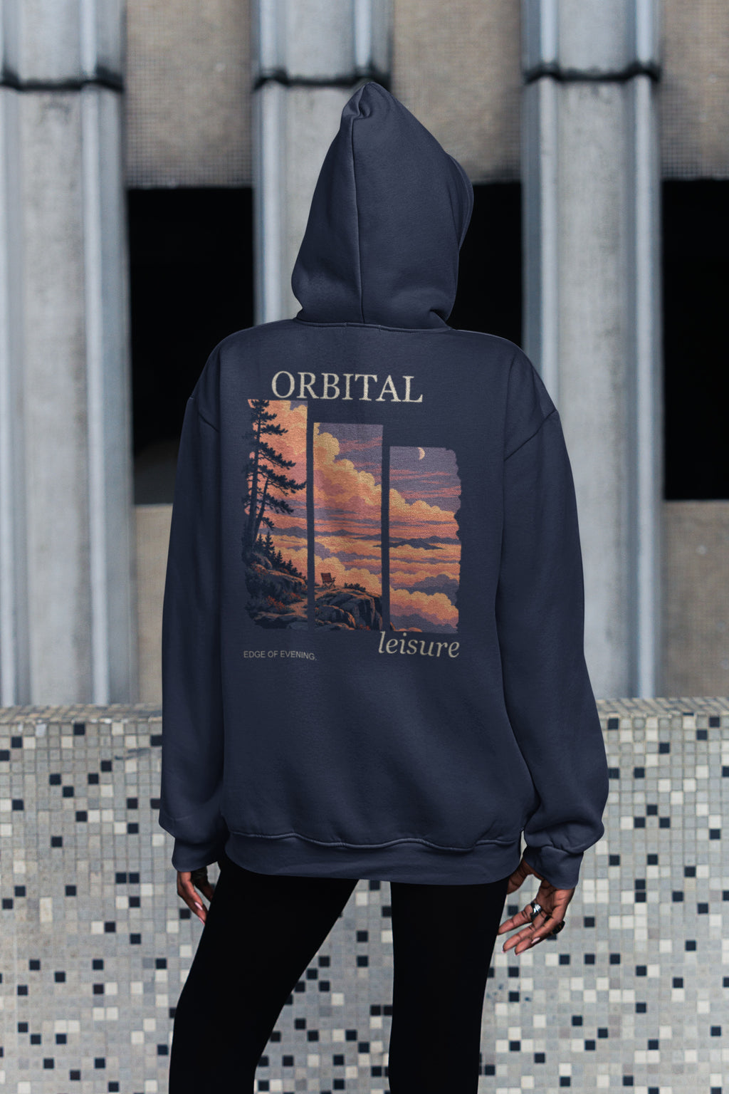 Edge of Evening Zip Hoodie in Navy, worn by a woman seen from behind on a city sidewalk, showing the large print on the back. Digital product mockup.