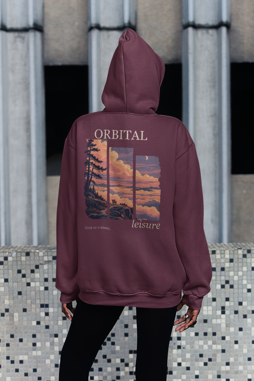 Edge of Evening Zip Hoodie in Maroon, worn by a woman seen from behind on a city sidewalk, showing the large print on the back. Digital product mockup.