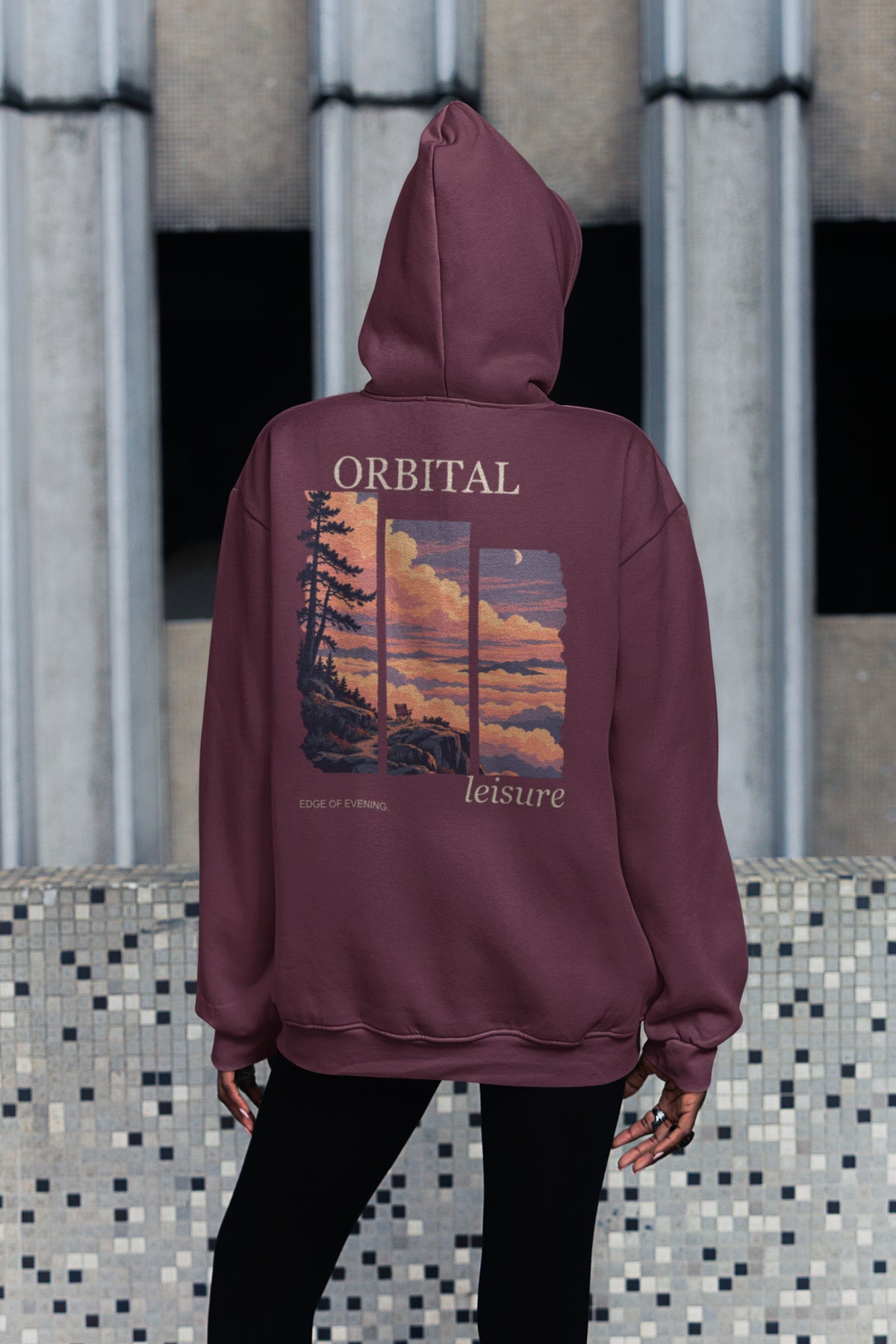 Edge of Evening Zip Hoodie in Maroon, worn by a woman seen from behind on a city sidewalk, showing the large print on the back. Digital product mockup.