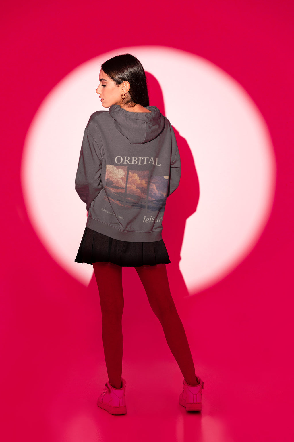 Stay for the Sky Zip Hoodie in Dark Heather, worn by a woman seen from behind in a studio spotlight, showing the large print on the back. Digital product mockup.
