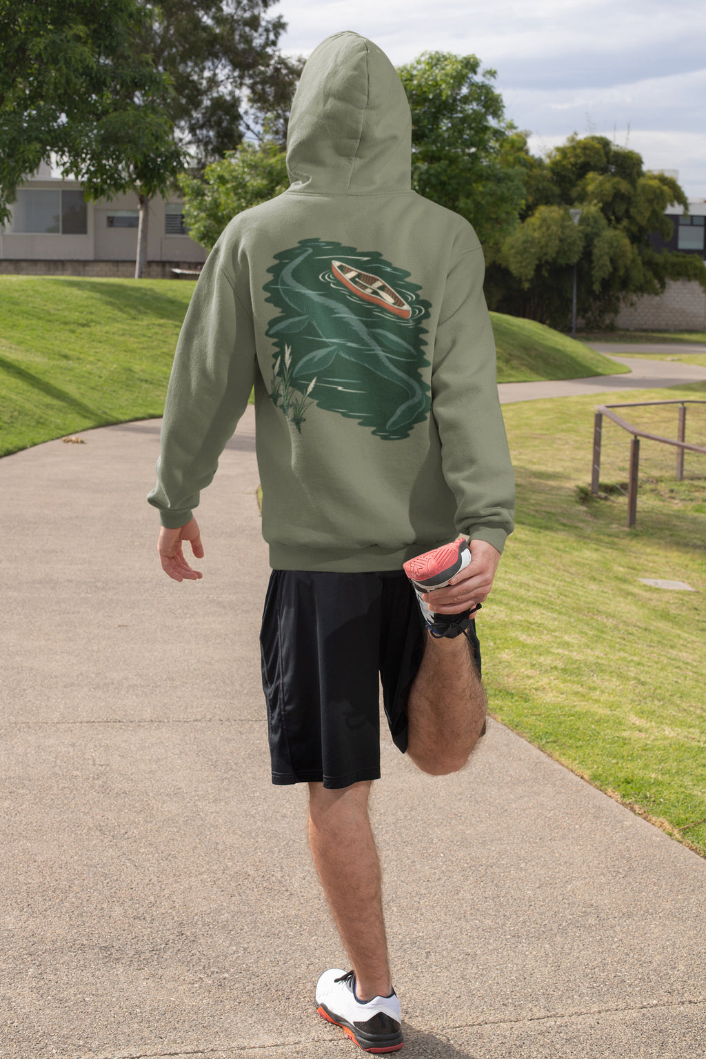 Seen Briefly Zip Hoodie in Military Green, worn by a man seen from behind on a sunny path, ready for a run, showing the large print on the back. Digital product mockup.