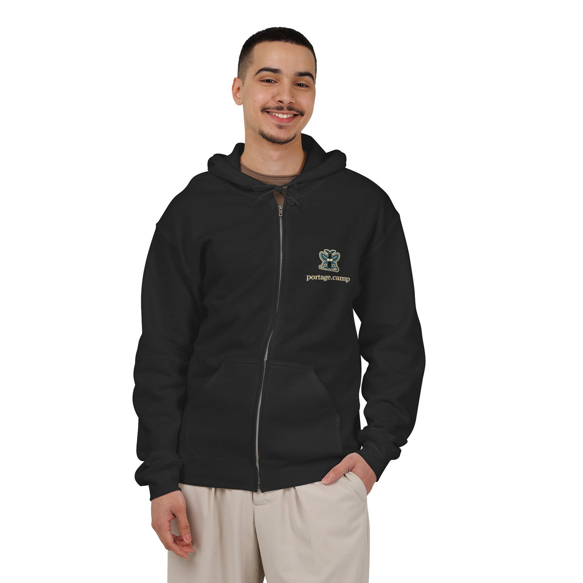 Night Library Zip Hoodie in Black, worn by a man in a plain white studio, with the Night Library logo and portage.camp on the left chest. Digital product mockup.