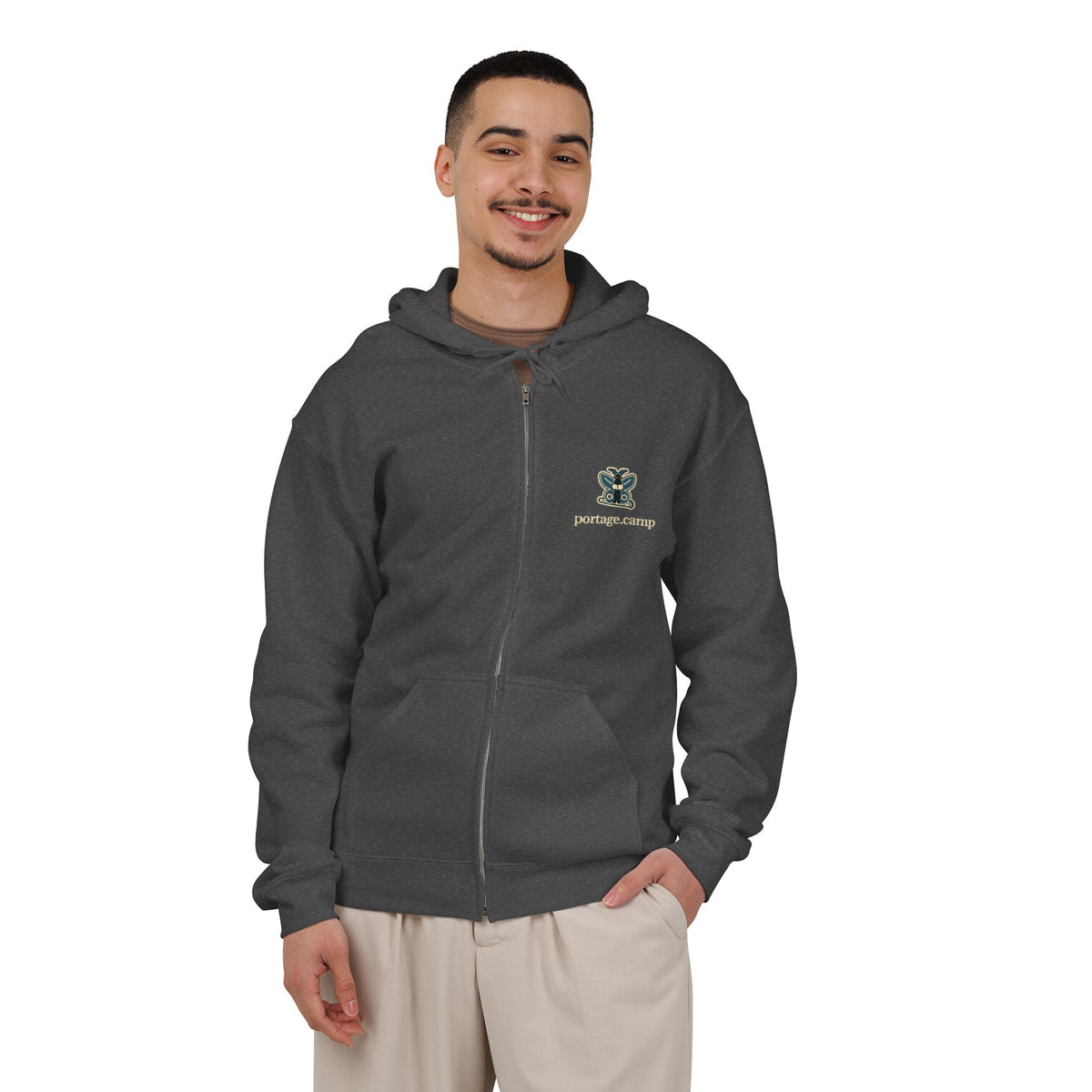 Night Library Zip Hoodie in Dark Heather, worn by a man in a plain white studio, with the Night Library logo and portage.camp on the left chest. Digital product mockup.