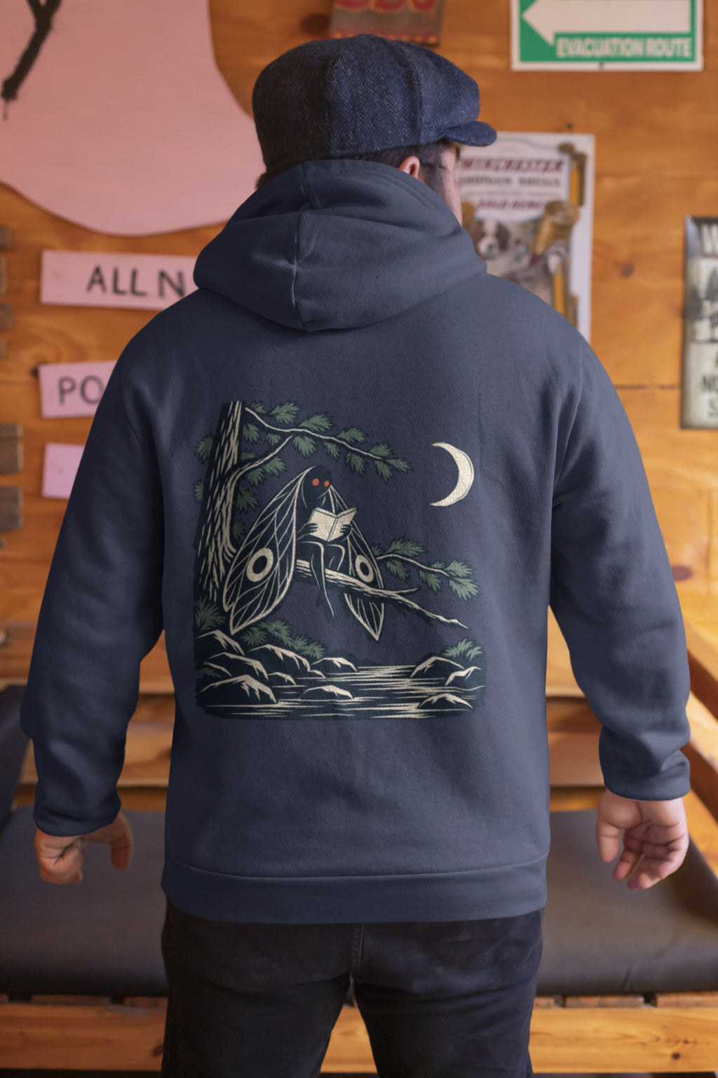 Night Library Zip Hoodie in Navy, worn by a man seen from behind in a wood-panelled bar, showing the large print on the back. Digital product mockup.