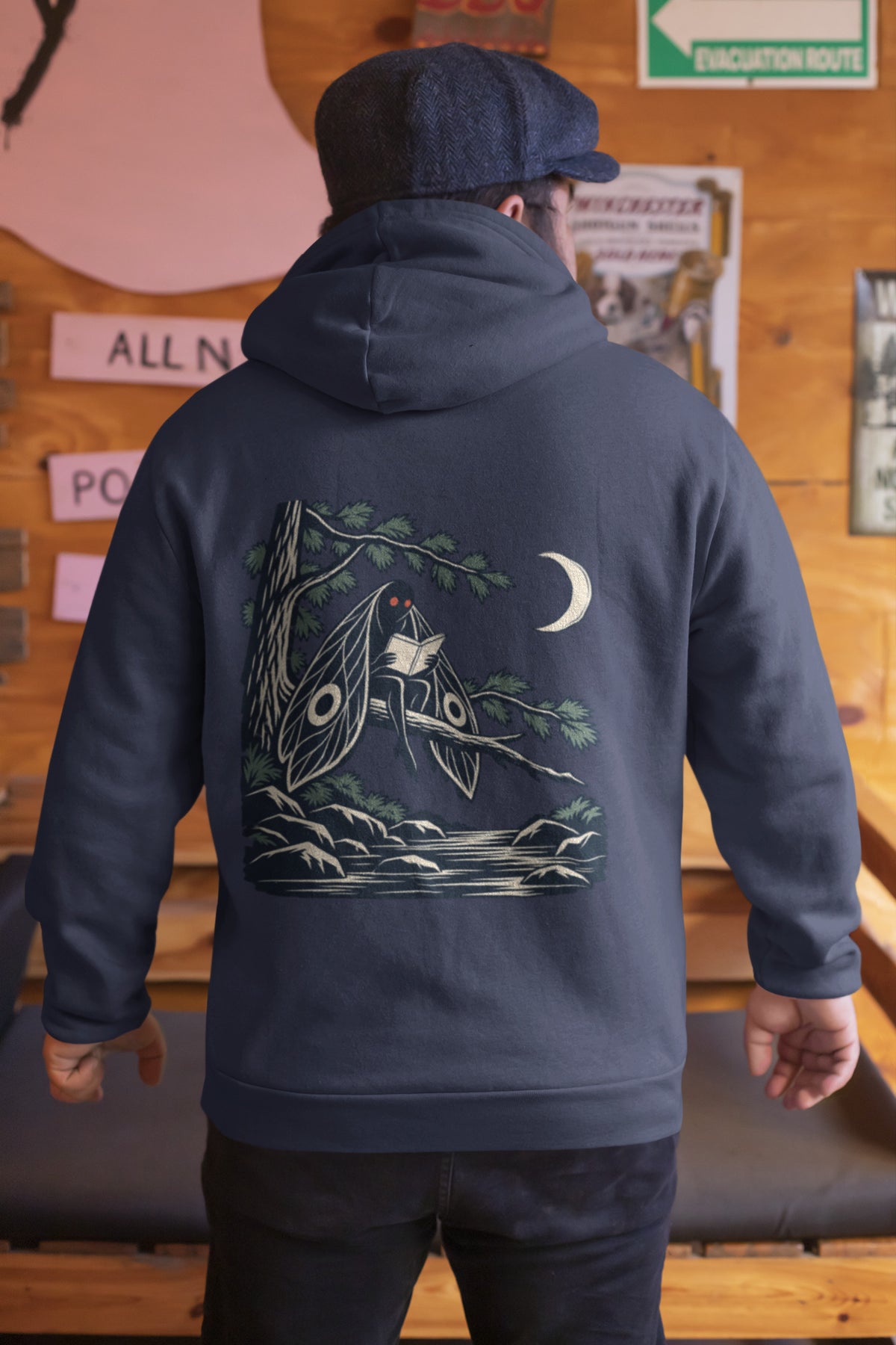 Night Library Zip Hoodie in Navy, worn by a man seen from behind in a wood-panelled bar, showing the large print on the back. Digital product mockup.