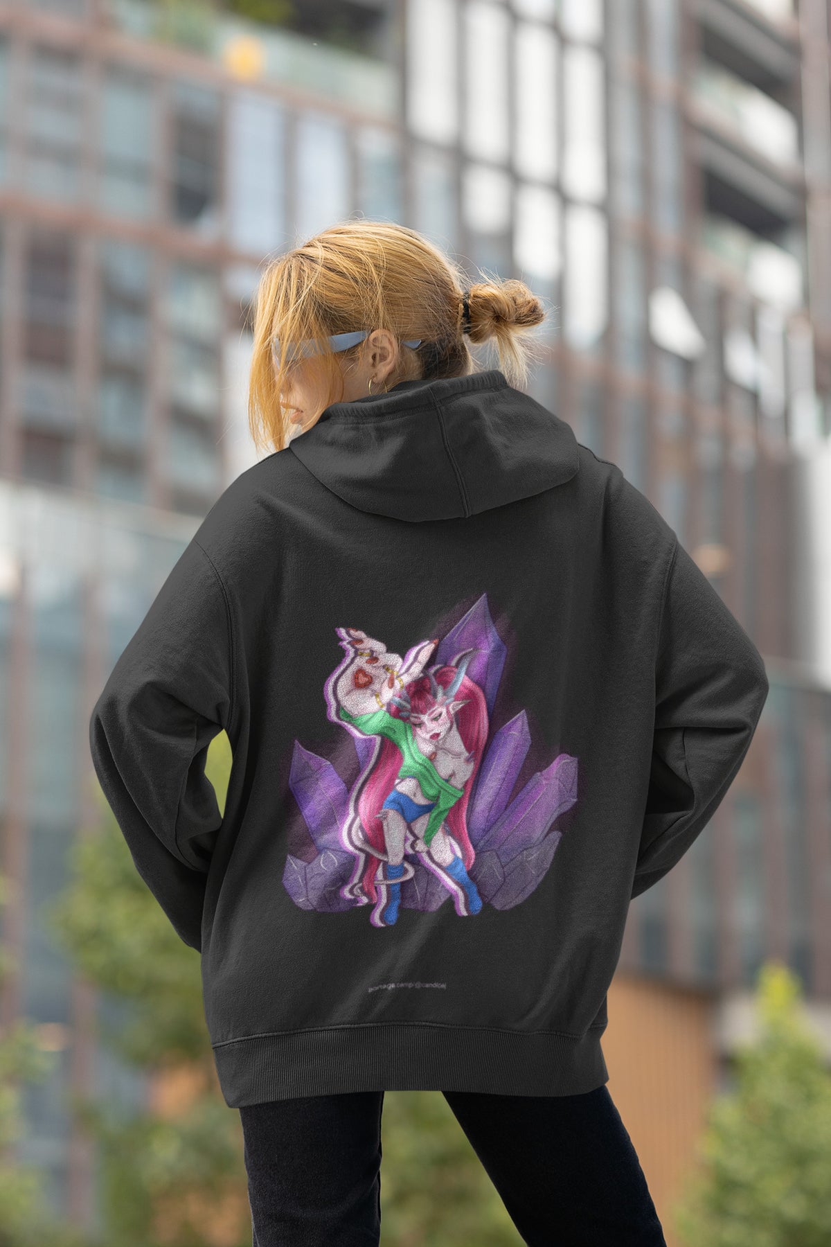 Heart Thief Zip Hoodie in Black, worn by a woman seen from behind by tall city buildings, showing the large print on the back. Digital product mockup.