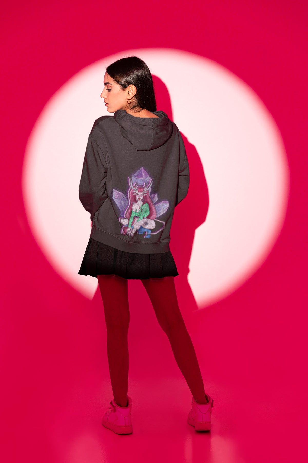 Amethyst After Hours Zip Hoodie in Black, worn by a woman seen from behind in a studio spotlight, showing the large print on the back. Digital product mockup.