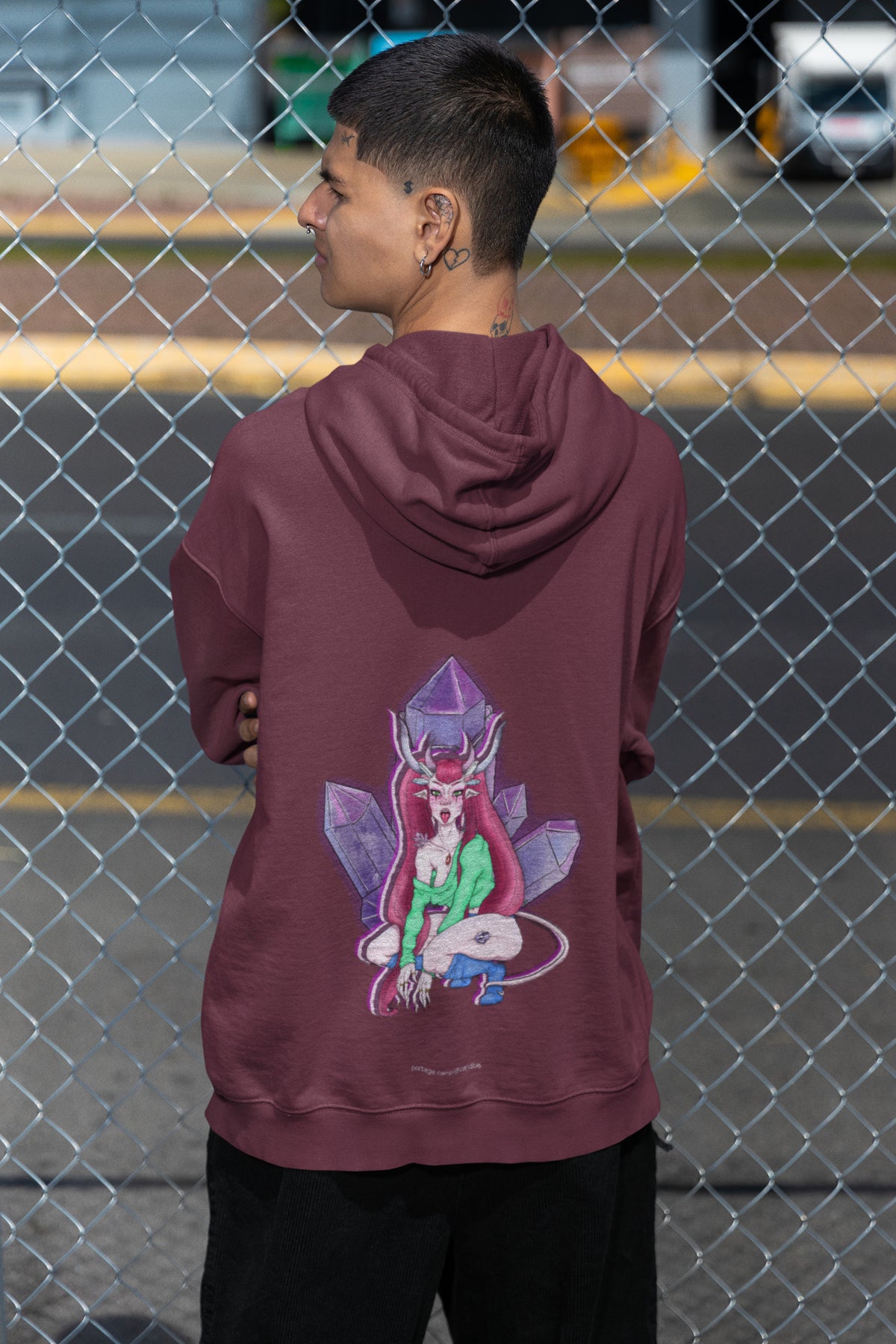 Amethyst After Hours Zip Hoodie in Maroon, worn by a man seen from behind by a chain-link fence, showing the large print on the back. Digital product mockup.