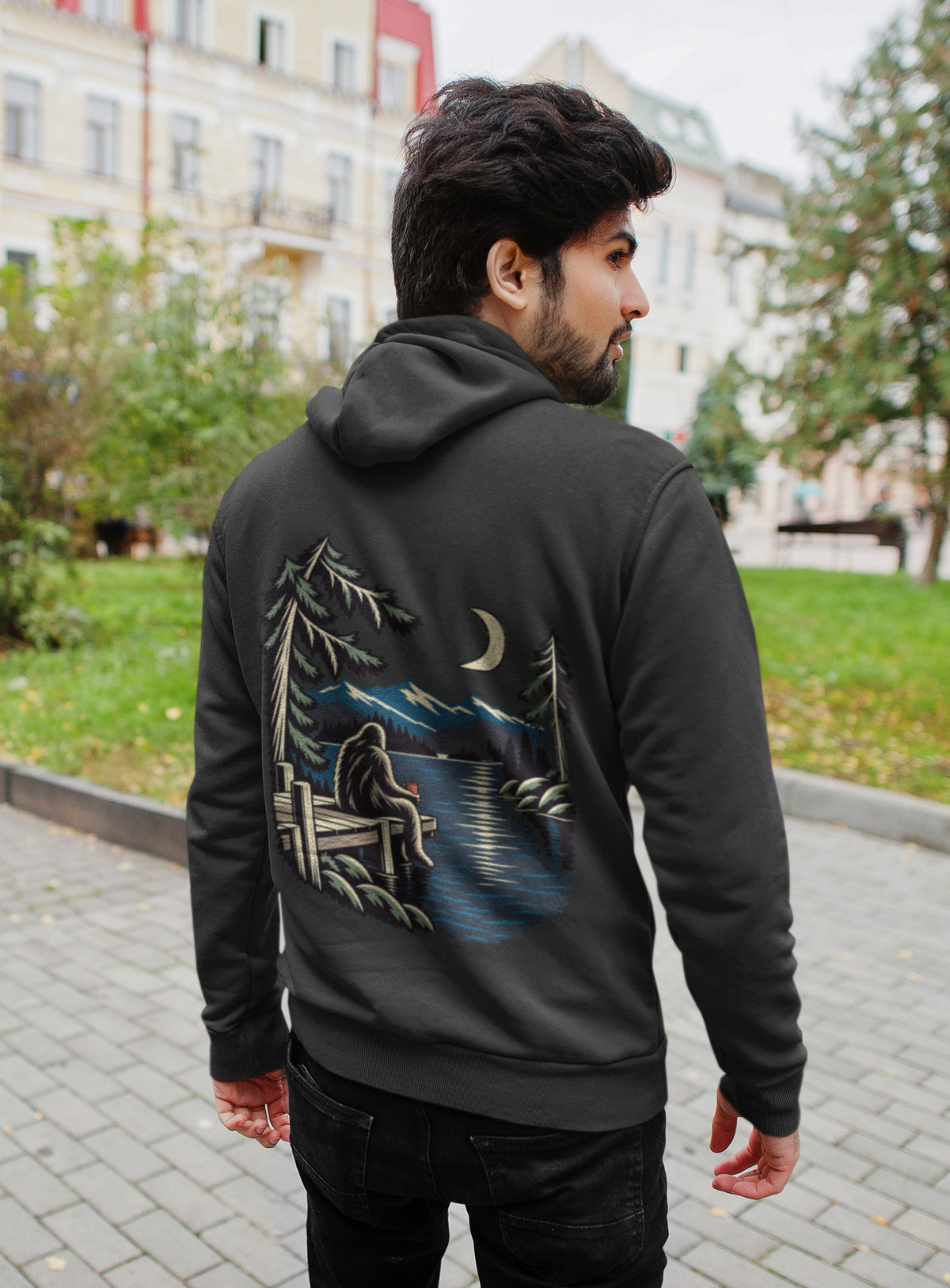 Quiet Hours Zip Hoodie in Black, worn by a man seen from behind on a quiet city street, showing the large print on the back. Digital product mockup.