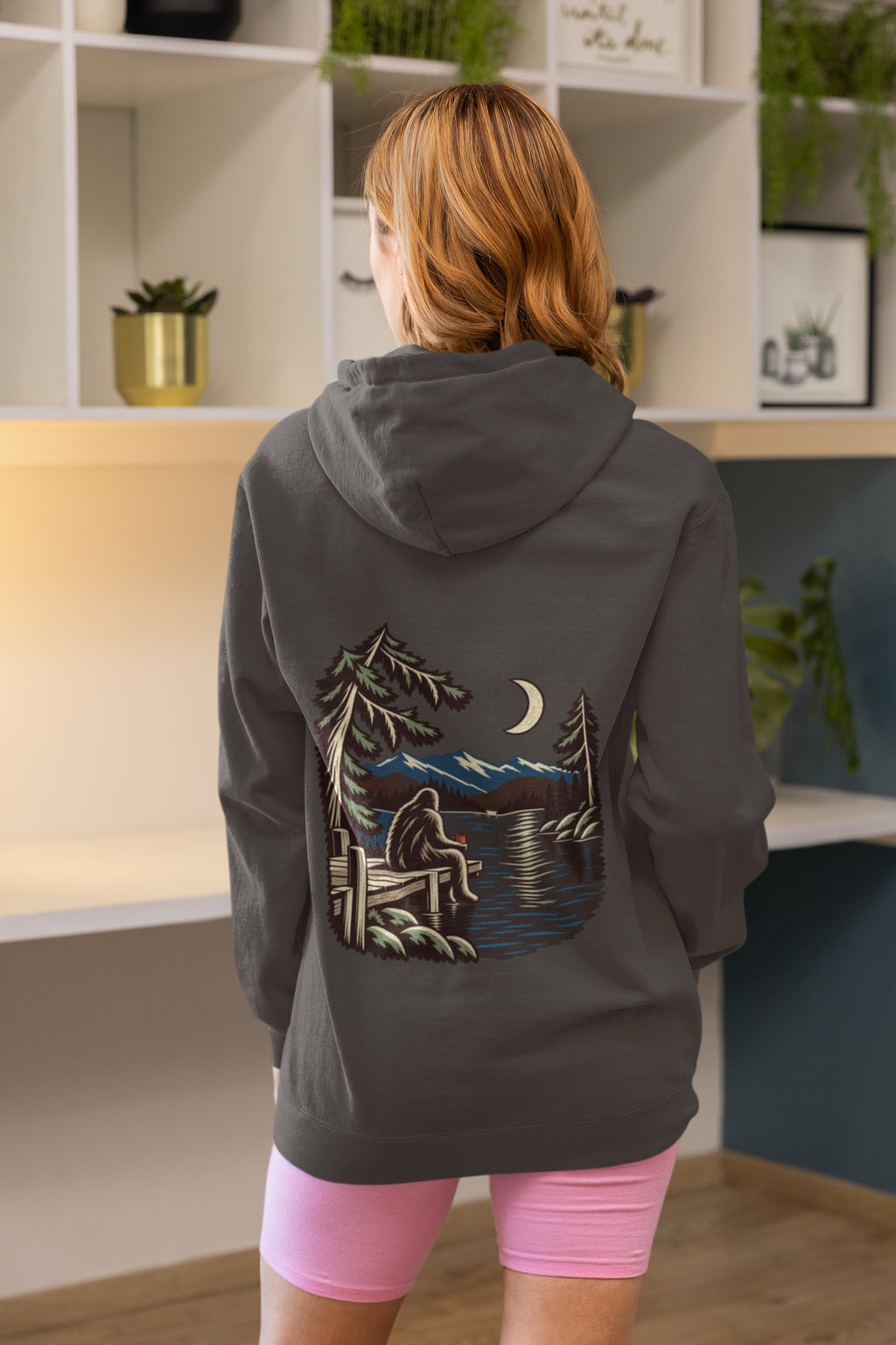 Quiet Hours Zip Hoodie in Dark Heather, worn by a woman seen from behind at home, showing the large print on the back. Digital product mockup.