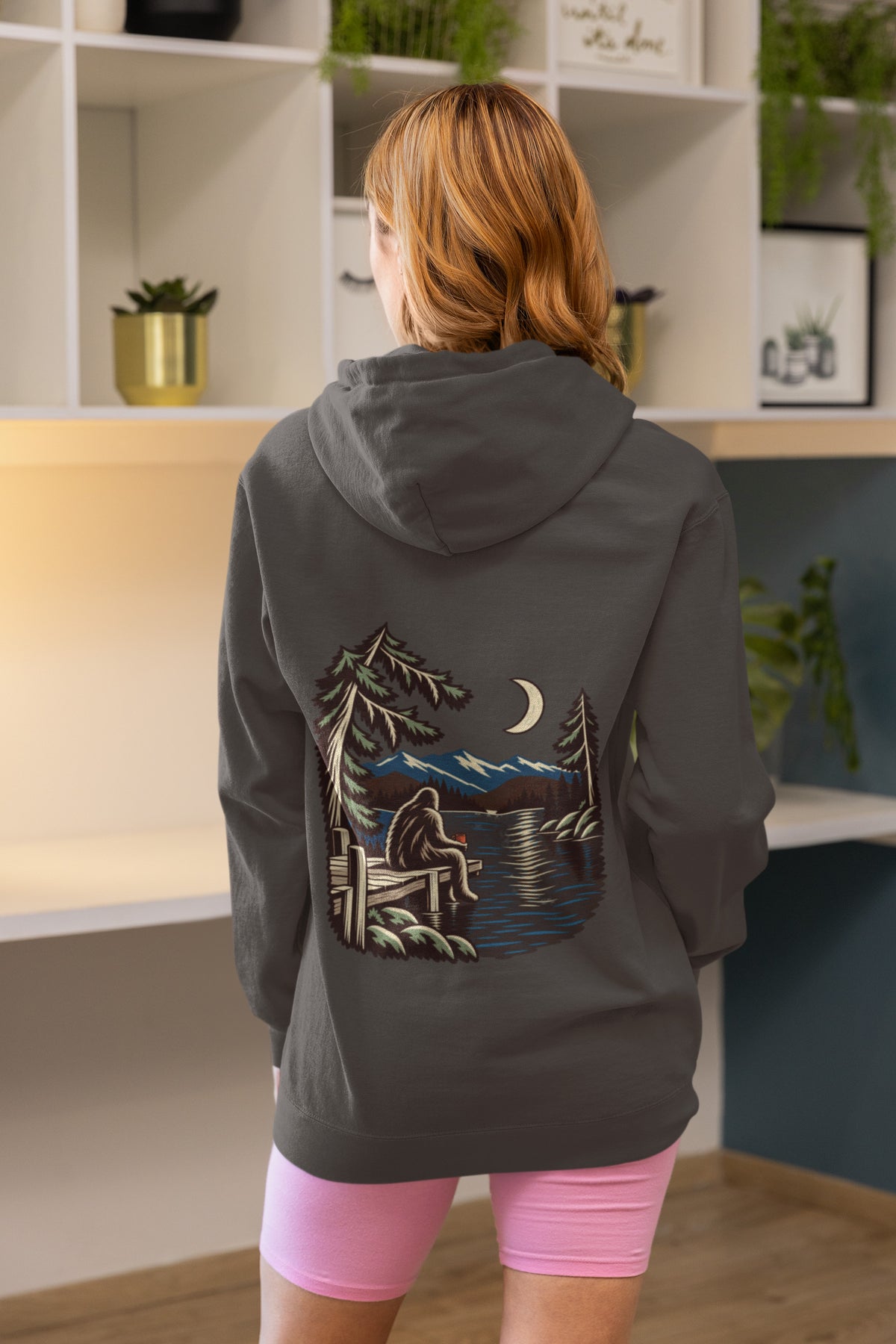 Quiet Hours Zip Hoodie in Dark Heather, worn by a woman seen from behind at home, showing the large print on the back. Digital product mockup.