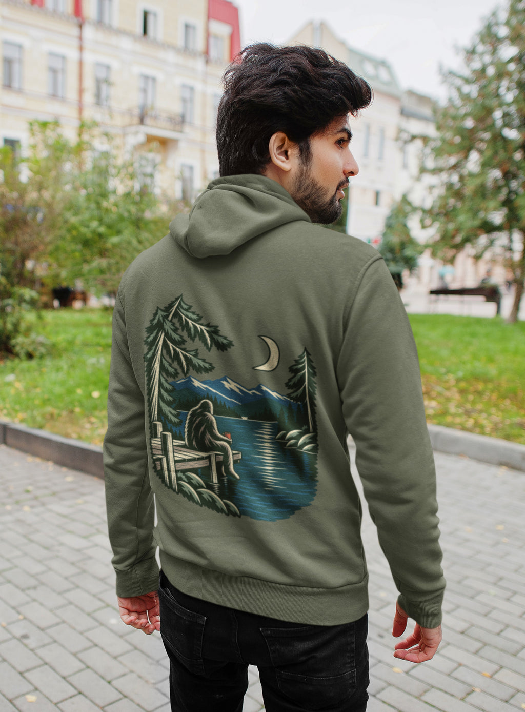 Quiet Hours Zip Hoodie in Military Green, worn by a man seen from behind on a quiet city street, showing the large print on the back. Digital product mockup.