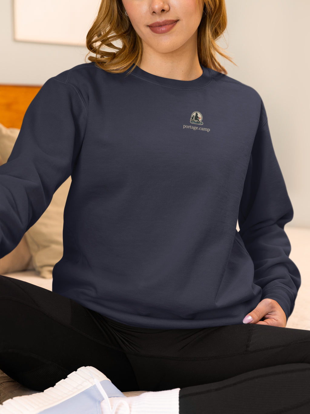Quiet Hours Garment-Dyed Crewneck in True Navy, worn by a woman at home, with the Quiet Hours logo and portage.camp on the chest. Digital product mockup.