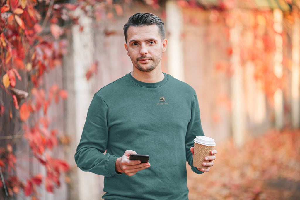 Quiet Hours Garment-Dyed Crewneck in Blue Spruce, worn by a man among autumn leaves, with the Quiet Hours logo and portage.camp on the chest. Digital product mockup.