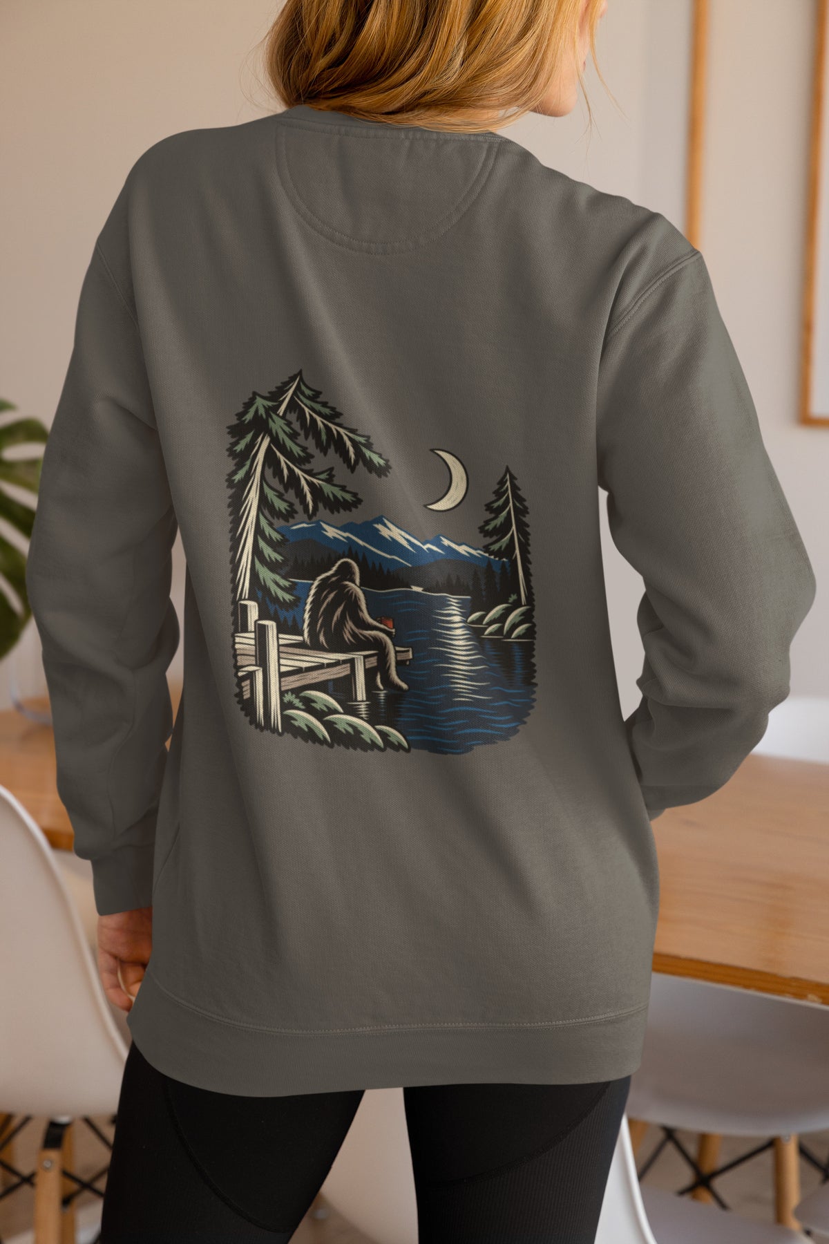 Quiet Hours Garment-Dyed Crewneck in Pepper, worn by a woman seen from behind at home, showing the large print on the back. Digital product mockup.
