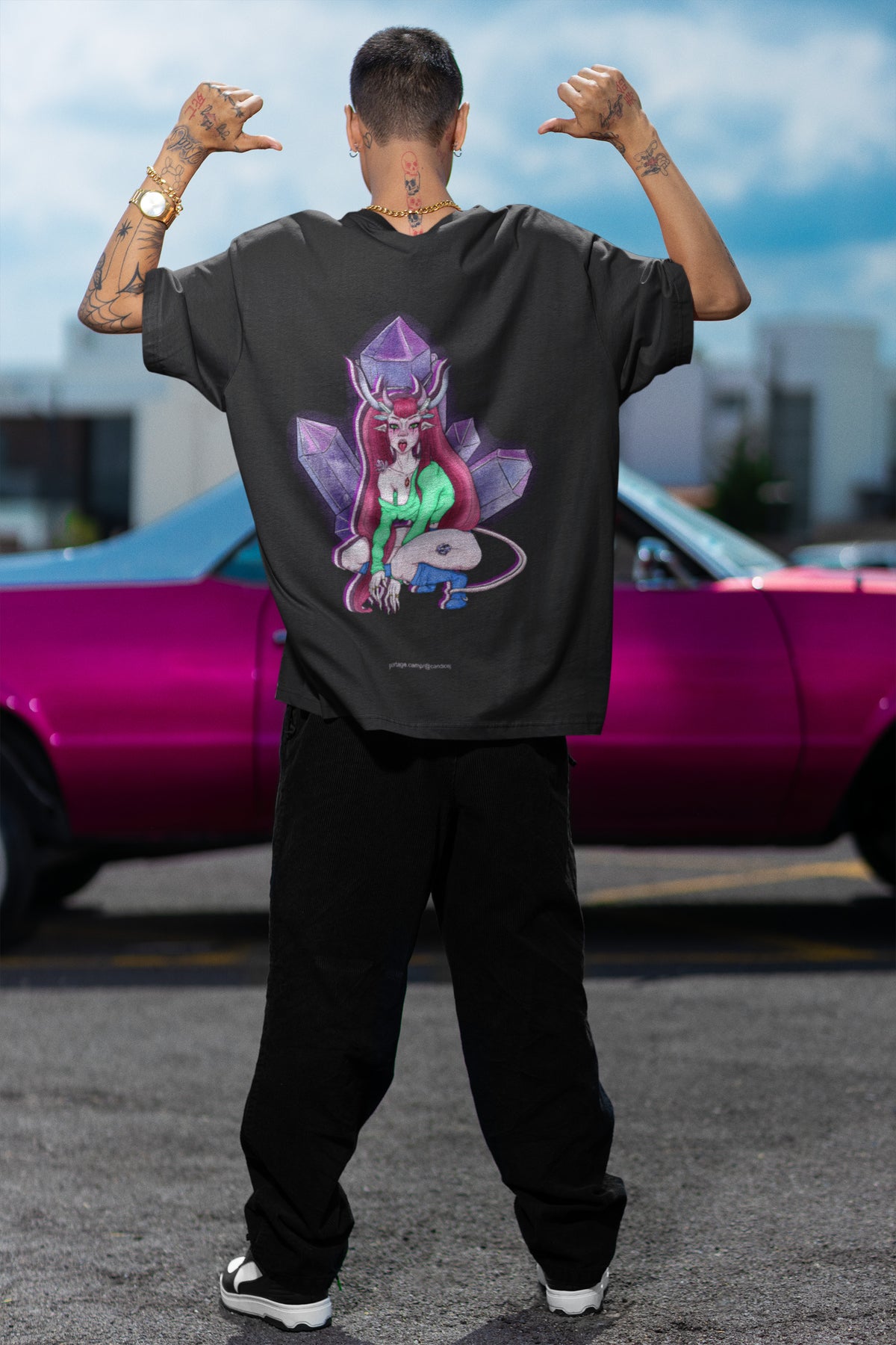 Amethyst After Hours Garment-Dyed Tee in Black, worn by a man seen from behind by a pink car, showing the large print on the back. Digital product mockup.