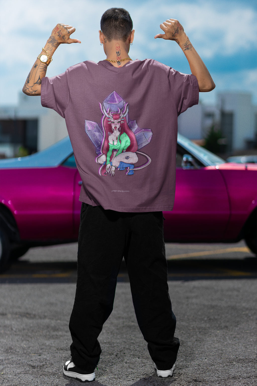 Amethyst After Hours Garment-Dyed Tee in Berry, worn by a man seen from behind by a pink car, showing the large print on the back. Digital product mockup.